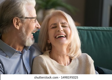 Laughing, closing eyes middle aged happy family couple close up. Senior gray-haired husband embracing, joking, having fun with elder positive attractive wife, head shot. Romantic anniversary