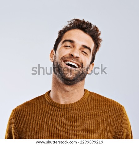 Laughing, comedy and portrait of happy man by white background. Smile, confident and face laugh of comic person, isolated and young male model enjoying a comedy joke on a studio backdrop
