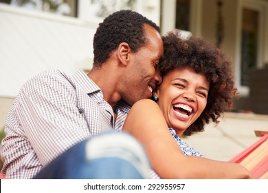 Laughing couple cuddling in a hammock