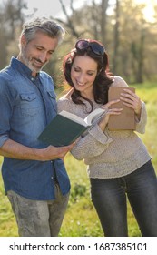 Laughing Couple Reading A Funny Book Outdoors 