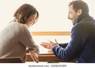 Laughing couple in sweaters at table - Powered by Shutterstock