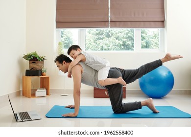 Laughing Cute Little Boy Interfering His Dad Following Tutorial On Laptop Screen When Practicing Yoga At Home