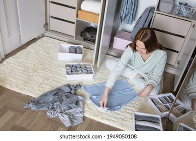 Laughing Domestic Woman Rolled Up Clothes Use Marie Kondo's Method. Happy Female In Pajamas Placing Apparel In Cupboard Organizing Storage At Home. Smiling Housewife General Cleaning At Wardrobe