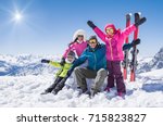 Laughing family in winter vacation with ski sport on snowy mountains. Happy man and woman with sons having fun and looking at camera. Family with two children enjoying winter holiday at ski resort.