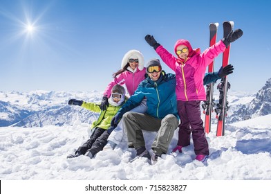 Laughing Family In Winter Vacation With Ski Sport On Snowy Mountains. Happy Man And Woman With Sons Having Fun And Looking At Camera. Family With Two Children Enjoying Winter Holiday At Ski Resort.