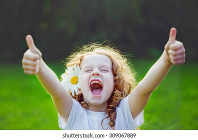 Laughing girl with daisy in her hairs, showing thumbs up. - Shutterstock ID 309067889