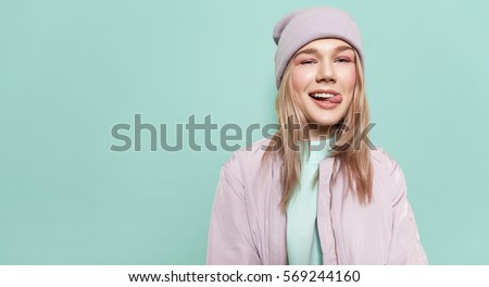 Laughing girl in a  in stylish casual clothes and shows tongue