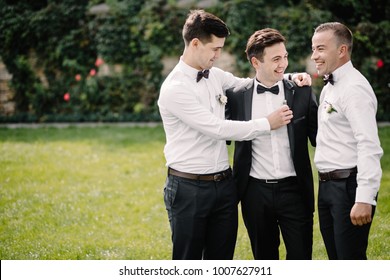 Laughing Groomsmen In Suits Hold Smiling Groom Under His Arms