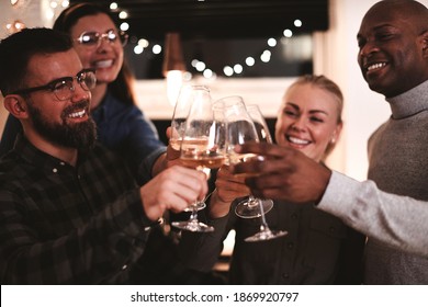 Laughing group of friends making a toast together with wine in a kitchen before an evening dinner party - Powered by Shutterstock