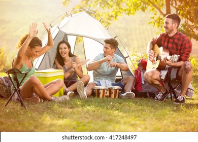 
Laughing Group Of Young People Enjoy In Music Of Drums And Guitar On Camping Trip