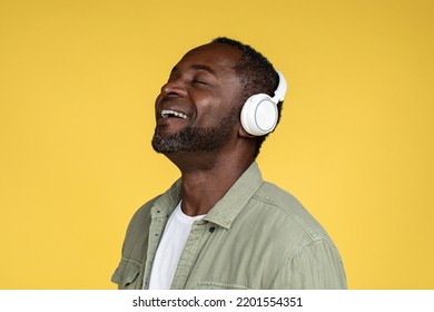 Laughing Handsome Middle Aged African American Male In Casual With Wireless Headphones Enjoy Music, Isolated On Yellow Background, Close Up, Studio. Rest, Relax And Fun, Superstar With Audio App