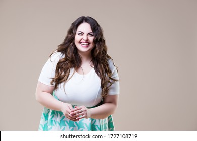 Laughing happy plus size model in casual clothes, fat woman on beige background, body positive concept