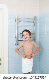 Laughing Happy Small Caucasian Boy In White Towel Stand In Blue Bathroom Indoors After Bathe