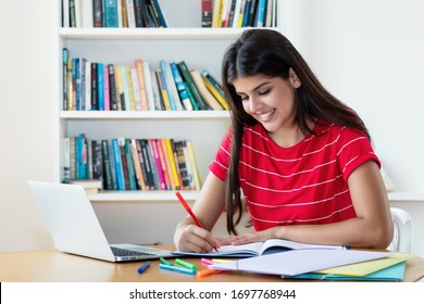Laughing hispanic female student learning language online using computer at home
