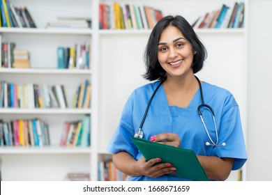 Laughing Hispanic Nurse Wirh File Of Patient At Hospital