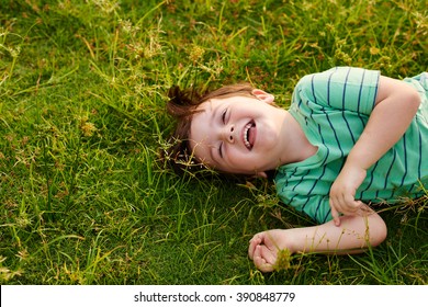 Laughing Kid Lying On Green Grass In The Park