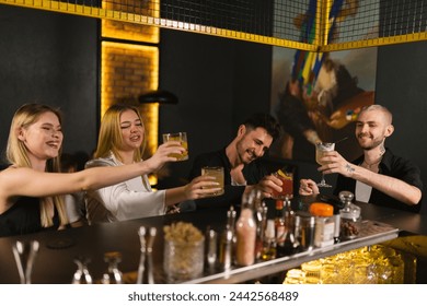 Laughing ladies and men in evening dresses drink alcoholic cocktails. Company spends time talking about fun topics after hard work week - Powered by Shutterstock