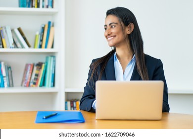 Laughing Latin American Mature Businesswoman With Blazer At Computer At Office