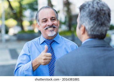 Laughing Latin American Senior Adult Businessman Showing Thumb Up To Employee Outdoor In City In Summer