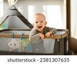 Laughing little boy in a travel cot