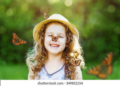 Laughing little girl with a butterfly on his nose. Happy childhood concept.