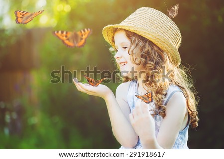Laughing little girl with a butterfly on his hand. Happy childhood concept. 