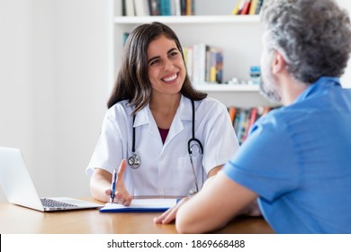 Laughing Mexican Female Doctor Talking With Patient At Hospital