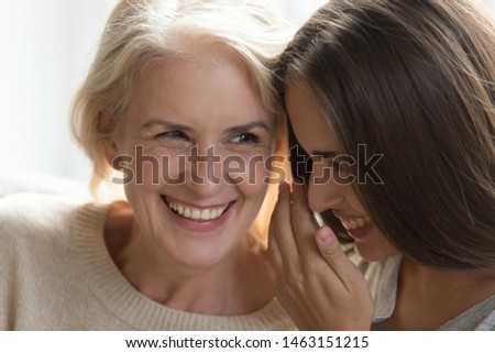 Laughing middle aged mother daughter gossiping sit close to each other spend enjoy time together, grandmother adult granddaughter best friends, intimates trusted person, love devotion, close up image