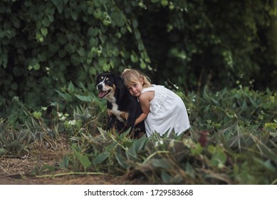 Laughing Mom Kneeling Down To Hug 4 Yr Old Daughter Near Lush Plants