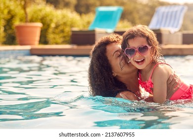 Laughing Mother And Daughter Wearing Sunglasses Having Fun In Swimming Pool On Summer Vacation - Powered by Shutterstock