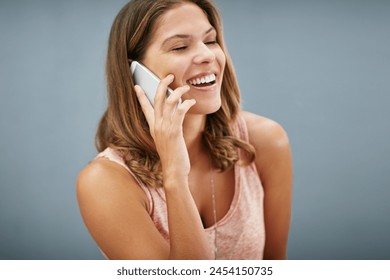 Laughing, phone call and happy woman talking in studio for story, gossip or news discussion isolated on a gray background. Mobile, smile and funny model in conversation, chat and listening to contact - Powered by Shutterstock