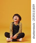 Laughing, portrait and smile of Asian boy on yellow background, isolated in studio for child development. Comedy, funny or silly and excited kid on mockup space for emotions, fashion or growth