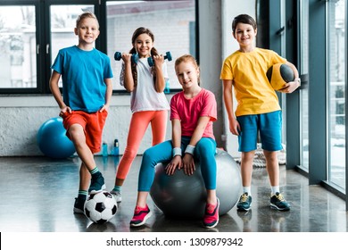 Laughing preteen kids posing with sport equipment