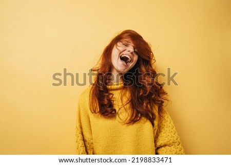 Laughing redhead woman with yellow sweater is happy copyspace against yellow background