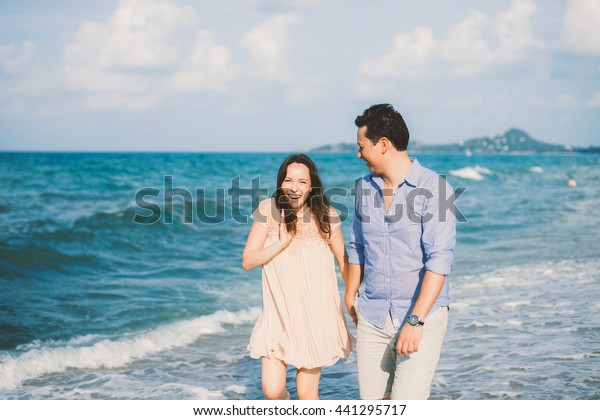 Laughing Romantic teenage hikers\
couple sitting on the hood of their car while out on a road\
trip.woman kissing boyfriend,smiling,outdoors.teen,purse,hat,Couple\
having fun on road trip on a summer\
day
