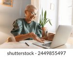 Laughing senior female school principal gesticulating while video chatting with teachers or colleagues, having online meeting. Businesswoman smiling during web conference with partners