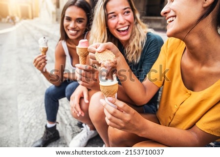 Laughing teenage girls eating ice cream cones on city street - Young female friends enjoying icecream outside - Summer lifestyle concept