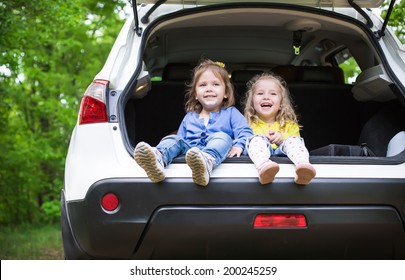 Laughing Toddler Girls Sitting In The Car In The Forest