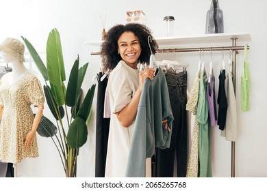 Laughing Woman Customer Choosing Sweatshirt In A Small Boutique