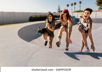 Laughing women climbing a skateboard ramp. Group of girls having a great time at skate park. - Powered by Shutterstock