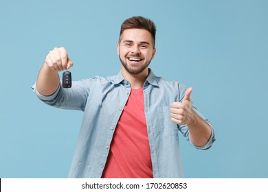 Laughing young bearded guy 20s in casual shirt posing isolated on pastel blue wall background studio portrait. People emotions lifestyle concept. Mock up copy space. Hold car keys, showing thumb up