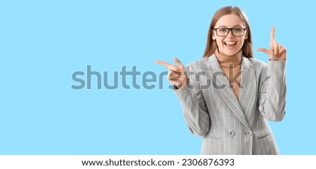 Laughing young businesswoman showing loser gesture on light blue background with space for text