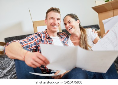 Laughing Young Couple With Blueprint Looking Forward To The New House As A Home