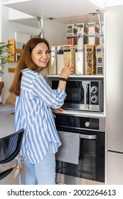 Laughing Young Female Housewife Posing During General Cleaning, Tidying Up In Cupboard Kitchen. Woman Placing, Sorting Food Into Pp Boxes For Comfortable Storage At Cuisine Having Positive Emotion