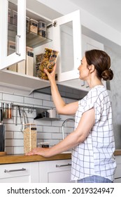 Laughing Young Female Housewife Posing During General Cleaning, Tidying Up In Cupboard Kitchen. Woman Placing, Sorting Food Into Pp Boxes For Comfortable Storage At Cuisine Having Positive Emotion