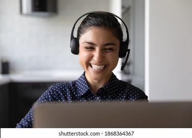 Laughing young indian woman sitting in earphones by laptop screen listening to funny joke from colleague. Excited hindu lady student receiving praise high grade from teacher at video conference online - Shutterstock ID 1868364367