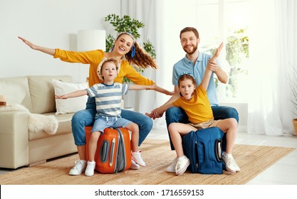 Laughing Young Man And Woman With Children Sitting On Suitcases At Home Holding Hands Apart In Flight Ready For Summer Vacation
