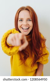 Laughing Young Redhead Woman Pointing At The Camera With A Vivacious Smile And Focus To Her Face
