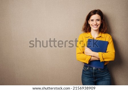 Laughing young woman against a brown background with her application documents in her hands