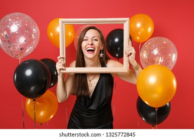 Laughing Young Woman In Little Black Dress Celebrating, Holding Picture Frame On Bright Red Background Air Balloons. St. Valentine's, Women's Day, Happy New Year Birthday Mockup Holiday Party Concept